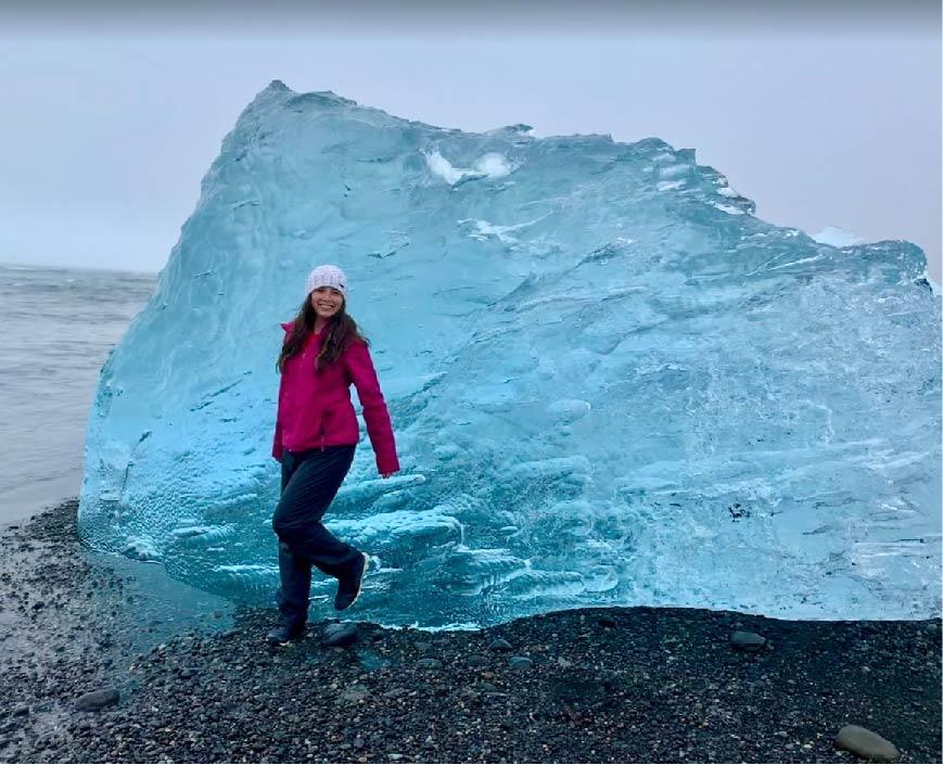 A student leans against a large ice block