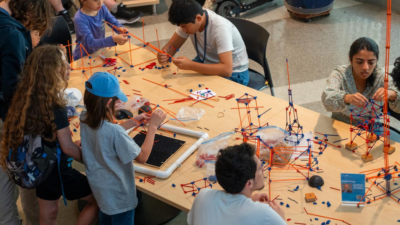Students crowding a table, building colorful STEM models with rods and connectors