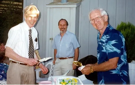 Photograph of Ray Krone on the left, Ian King in the middle, and Gerald Orlob on the right, celebrating over cake