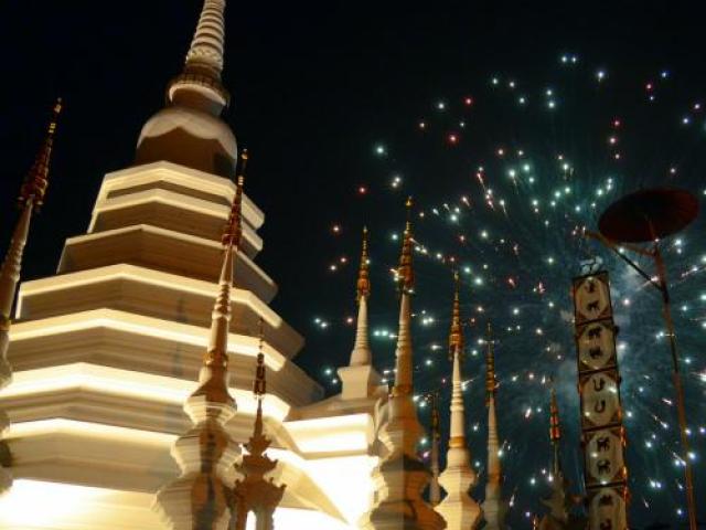 temple is lit from below in thailand with floating lanterns
