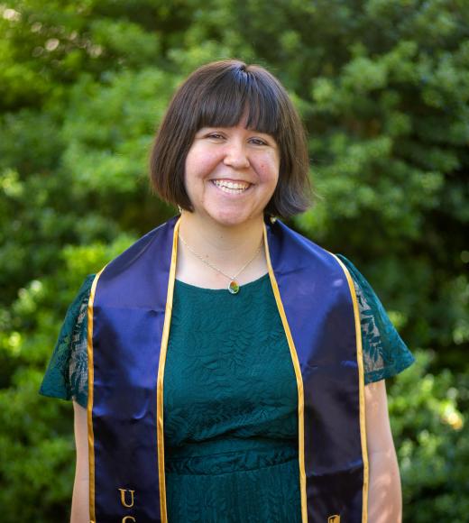 A woman wearing a UC Davis stole smiles