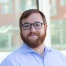 Photo of man with glasses and beard in front of window